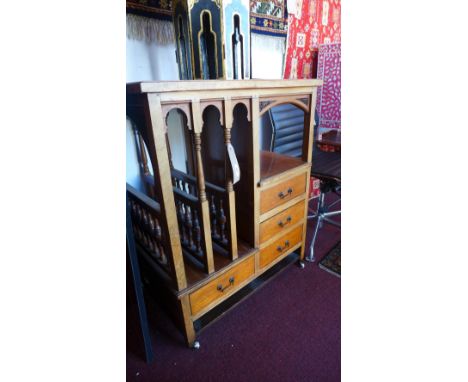 An Arts and Crafts oak side cabinet, having carved floral panels over turned magazine rack, a shelf and an arrangement of fou