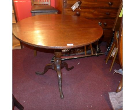 A Georgian oak tilt top occasional table raised on turned stem with tripod supports 