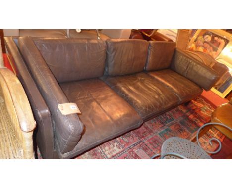 A 1970's Danish brown leather three seater sofa raised on ebonised square section supports