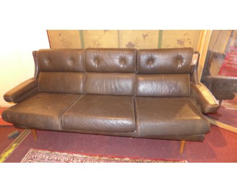 A vintage brown leather three seater sofa, with stitched edges raised on tapering supports