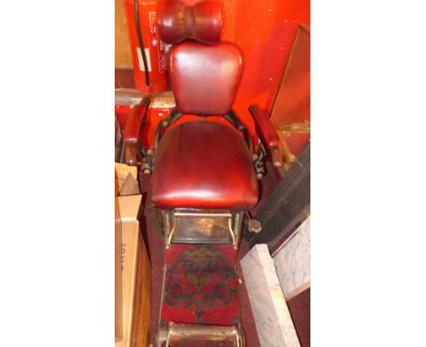 A vintage fully articulated dentist's chair in burgundy upholstery