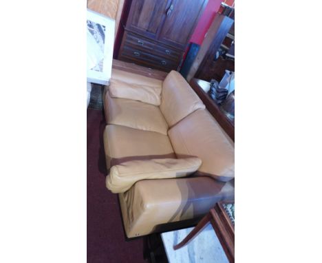 A Natuzzi tan leather two seater sofa raised on block supports 