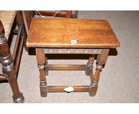 An early 20th Century oak joint stool, the rectangular seat above a carved frieze, raised on turned shaped legs joined by squ