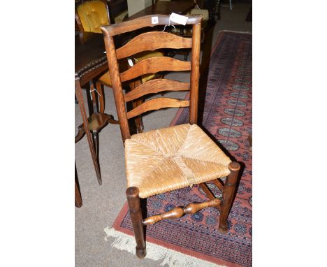 Three elm country dining chairs, the shaped cresting rail above ladder back and rush seats, raised on turned tapering legs jo
