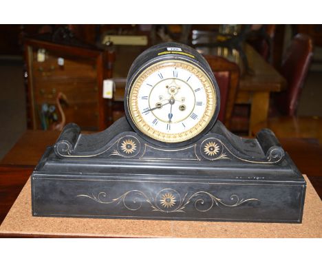 A Victorian mantel clock in black slate case, the white enamel roman dial with skeleton movement, the case carved in gilt wit