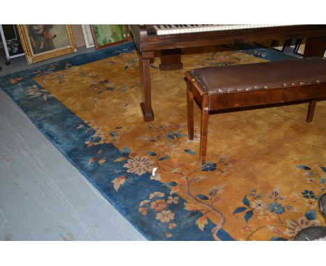 A Chinese style carpet, the mustard coloured field decorated with scattered floral design and blue border.