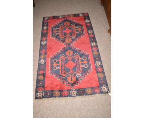 A Persian Beluche carpet, with two decorative medallions on claret ground, 58 x 33in. 