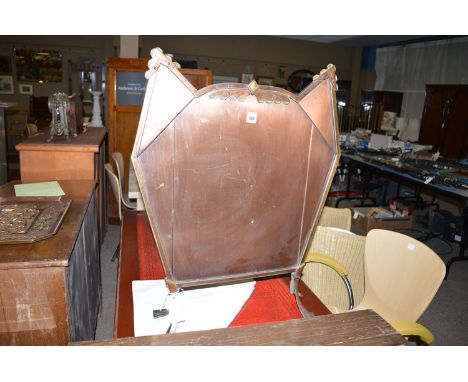 An Art Deco brass and copper fire screen of shaped form with flared splayed pattern feet.