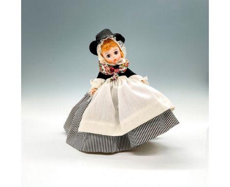 Doll is dressed in late 19th century British attire, a black hat and a colorful scarf around her shoulders. This item has a b