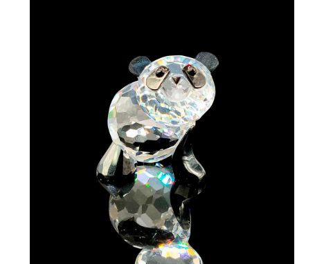 A clear crystal figure of a panda with one arm raised up, with black crystal used for the limbs, ears, and eyes. Swarovski ba