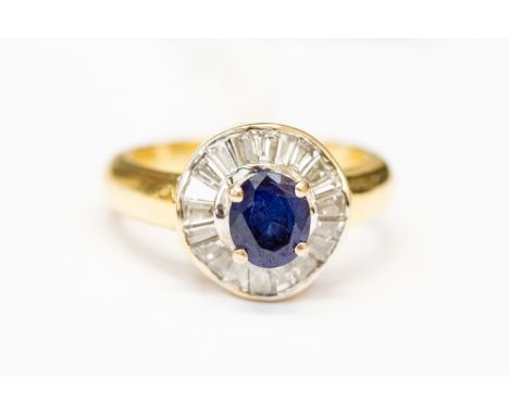 A sapphire and diamond set ring, central claw set oval sapphire with tapered baguette cut surround, size K, total gross weigh
