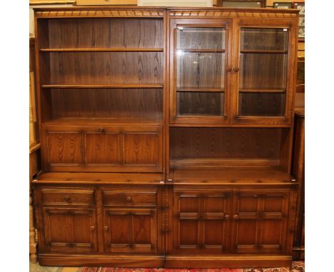 An Ercol elm side unit, the upper section fitted with two glazed doors enclosing shelves, the base with two panelled doors, e