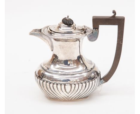 An Edwardian silver hot water jug, gadroon border and fluted body, hinged cover with ebonised pagoda finial, C-scroll ebonise