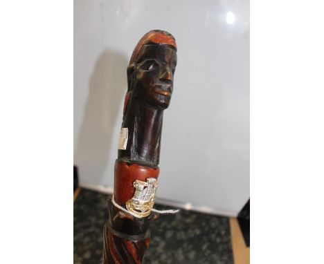 A hardwood carved African walking stick with man's head handle with a Devon and Dorset Regt Staybrite collar dog affixed.