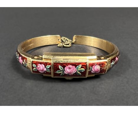 A ladies yellow metal bangle/watch, stamped '750', with red ground floral enamel decoration and hinged dial cover, lettered "