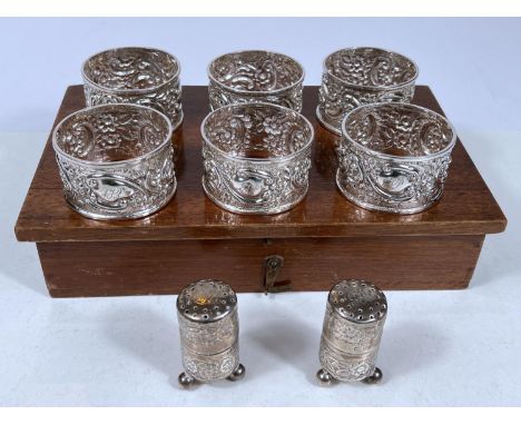 A hallmarked silver pair of salt shakers, embossed on 3 ball feet, Birmingham 1898; a set of 6 hallmarked silver embossed nap