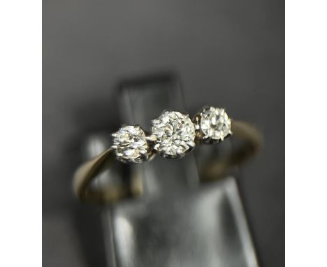 An 18ct gold dress ring set with three diamonds, large central and two smaller flanking, 3.6mm largest diamond, size L 