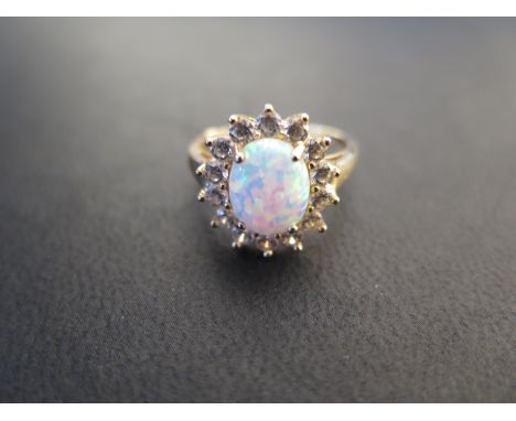 A 14ct yellow gold and oval opal dress ring, the opal being surrounded by clear stones - surface scratches, light usage wear 