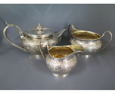 A Georgian silver hallmarked tea service consisting of tea pot, twin handled sugar and milk jug all with embossed foliate dec