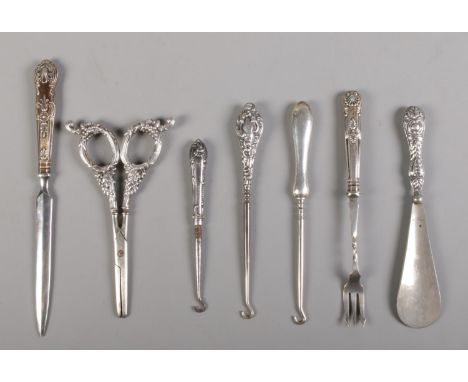A collection of silver and silver handled utensils; to include button hooks, letter opener and grape scissors.  