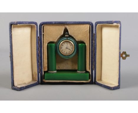 An Art Deco travelling clock in case. Possibly green bakelite housing a gilt metal timepiece.  