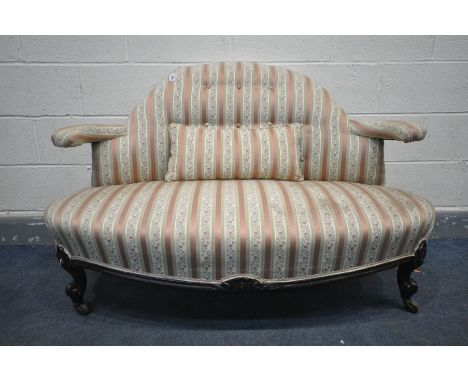 A LATE VICTORIAN CANAPE SOFA, with a shaped back and open arm rests, on scrolled front legs, a central support leg, and ceram