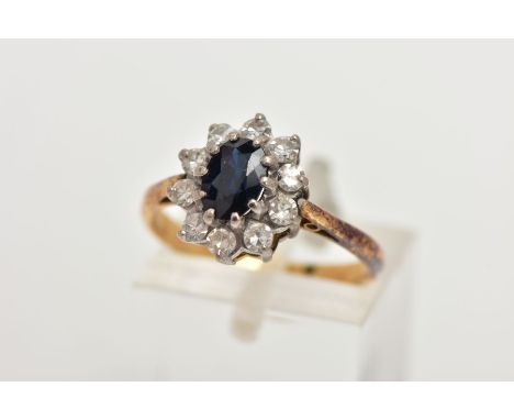 A YELLOW METAL SAPPHIRE AND DIAMOND CLUSTER RING, centring on an oval cut deep blue sapphire, within a surround of single cut