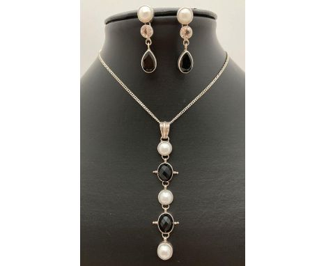 A modern design drop style pendant set with black spinel and white pearls on a 20 inch curb chain with spring clasp. With mat