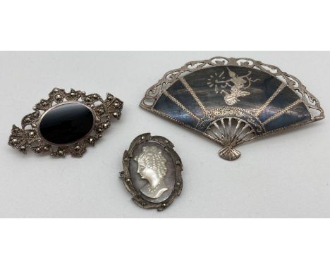 3 silver brooches. A fan brooch with Thai dancer design, a pierced work brooch set with central oval onyx and marcasite stone