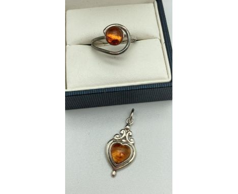 A small spiral design ring set with a round amber cabochon. Together with a modern design heart shaped amber set pendant with