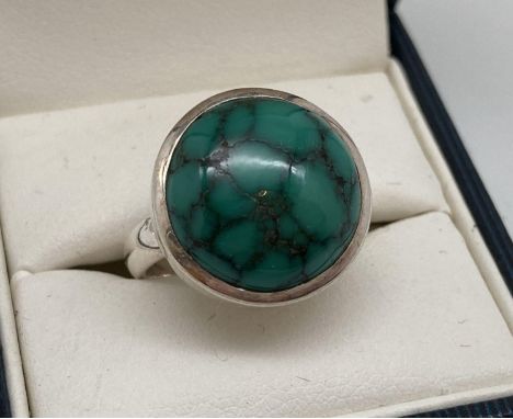 A modern design silver dress ring set with a round cabochon of green turquoise. Inside of band marked 925. Ring size N. 