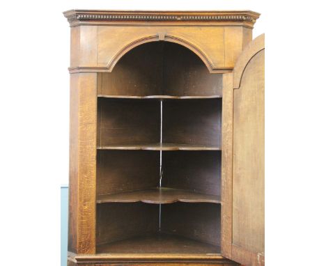 A large George III oak and mahogany cross banded full height corner cupboard, the panelled architectural top cupboard door en