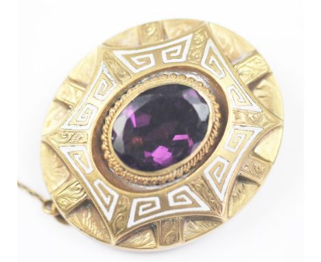 A Victorian amethyst coloured stone inset and yellow metal mourning brooch, the central oval cut stone within rope twist surr