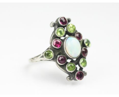 An Arts and Crafts opal, peridot and ruby set ring, in the manner of Sybil Dunlop, within hand wrought silver setting, with d