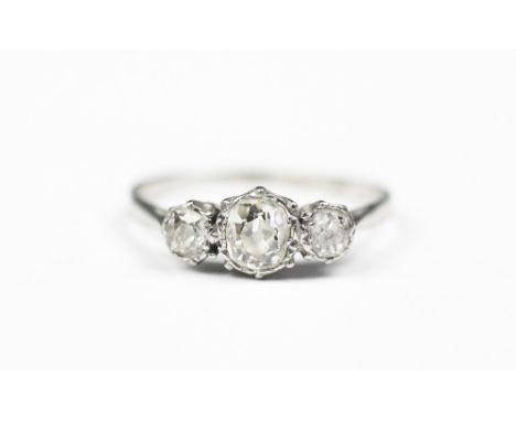 A three stone diamond ring, the three graduated old cut diamonds claw set in white metal to the tapering shoulders and plain 