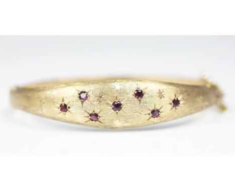 A 9ct yellow gold ruby set hinged bangle, Smith & Pepper Birmingham 1976, set with with seven graduated rubies in star settin