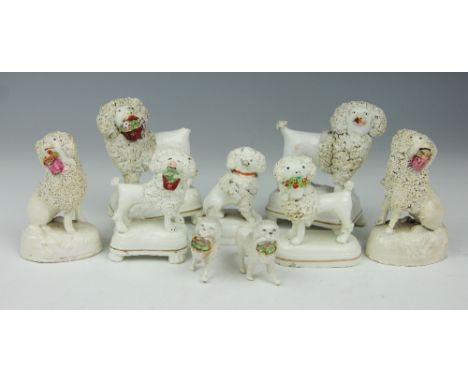 A collection of nine Staffordshire and other porcelain poodles, to include; standing and seated examples with baskets in thei