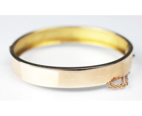 A 15ct yellow gold hinged bangle, 'CP&S' early 20th century, of plain form, with attached safety chain, weight 12.5gms 
