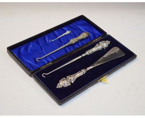 Edward VII embossed silver handled shoe horn and button hook, Birmingham 1904, cased, together with two other silver handled 