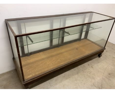 A large shop display showcase. Sliding doors to the rear with internal glass 2 piece shelf. W:179cm x D:59cm x H:94cm