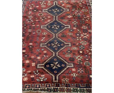 A Persian carpet, red field and blue central medallions with floral symbols. W:205cm x D:cm x H:270cm