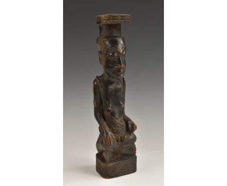 Tribal Art - a Kuba Ndop figure, carved as a portrait of a king, depicted seated, the cap and base carved with geometric moti