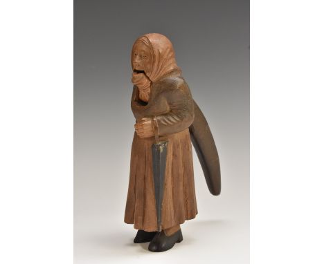 A Black Forest novelty lever-action nutcracker, carved as a lady, she stands, wearing a headscarf and holding an umbrella, 20