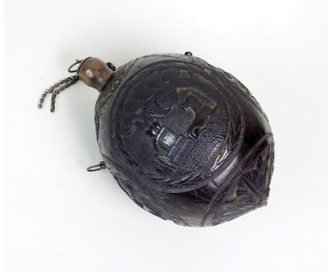 A carved coconut flask, late 18th/early 19th century, with two diminutive ring handles carved with a mask and flower sash nea