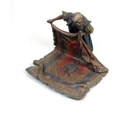 An Austrian cold painted bronze model of a carpet seller after Franz Bergman, early 20th century, the vendor slightly crouche