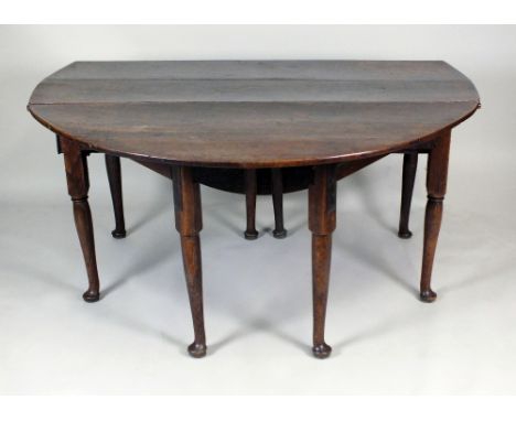 A George III double gate leg action oak farmhouse table, circa 1800, the oval planked drop leaf top above a single end frieze