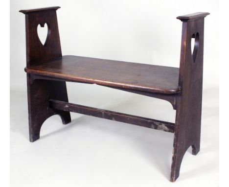 An oak hall bench, circa 1905, in the manner of Liberty, the rectangular seat with rounded corners and held by tapering panel