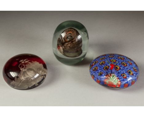 THREE GLASS PAPERWEIGHTS, one PROBABLY BOHEMIAN, red stained and intaglio cut with a resting stag, 3" (7.6cm) diameter, anoth