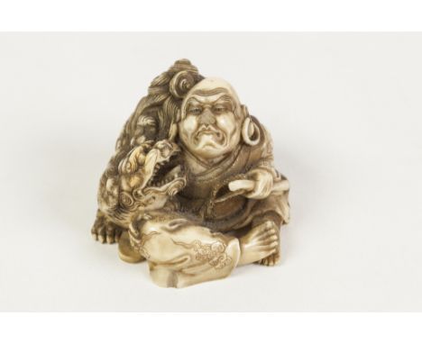 A FINELY CARVED JAPANESE MEIJI PERIOD IVORY NETSUKE OR SMALL OKIMONO, in the form of a mythical figure sat beside a shi-shi, 