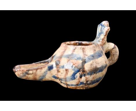 Ca. 1100-1200 AD.A pottery oil lamp, adorned with a captivating cream glaze embellished with vertical lines of brown and deli